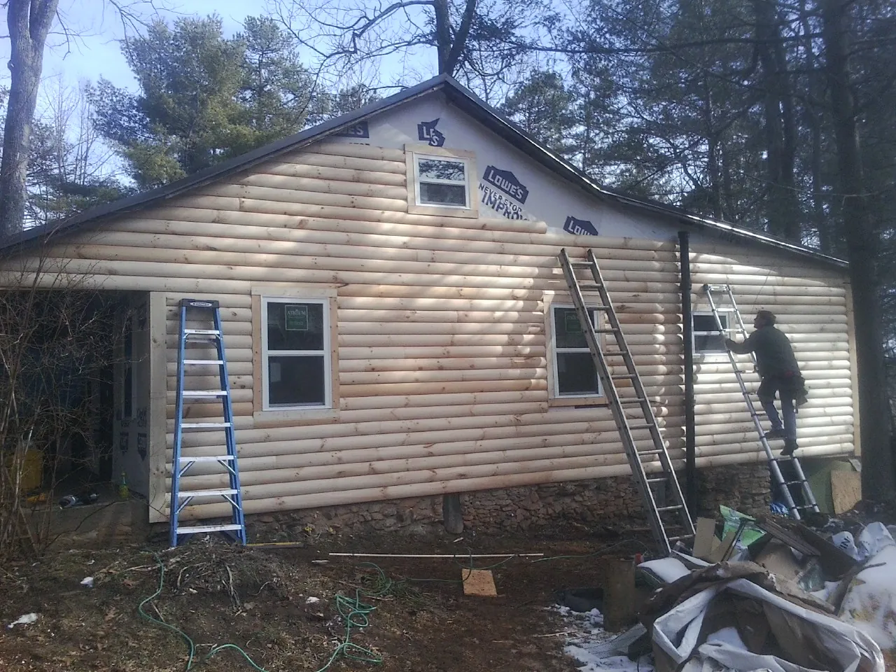 Ladders set against fresh log siding during an exterior remodel in Pinckney