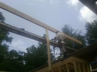 Carpenter setting a ridge beam over a new addition frame — Ice Dam Removal by Roofing Brothers in Pinckney