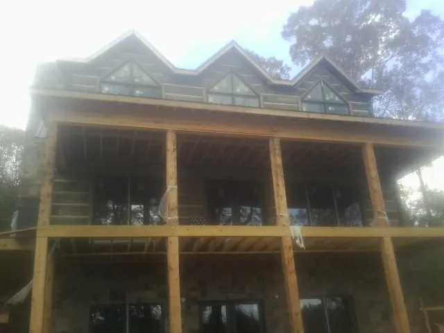 Dormers and porch framing on a large log home under construction — Roof Coating work by our crew in Pinckney