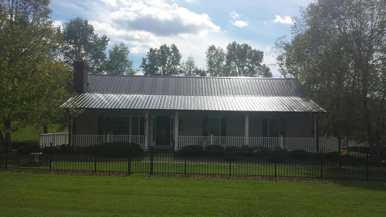 Gray metal roof on a brick ranch with a full width front porch — Gutter Guard Installation work by our crew in Pinckney