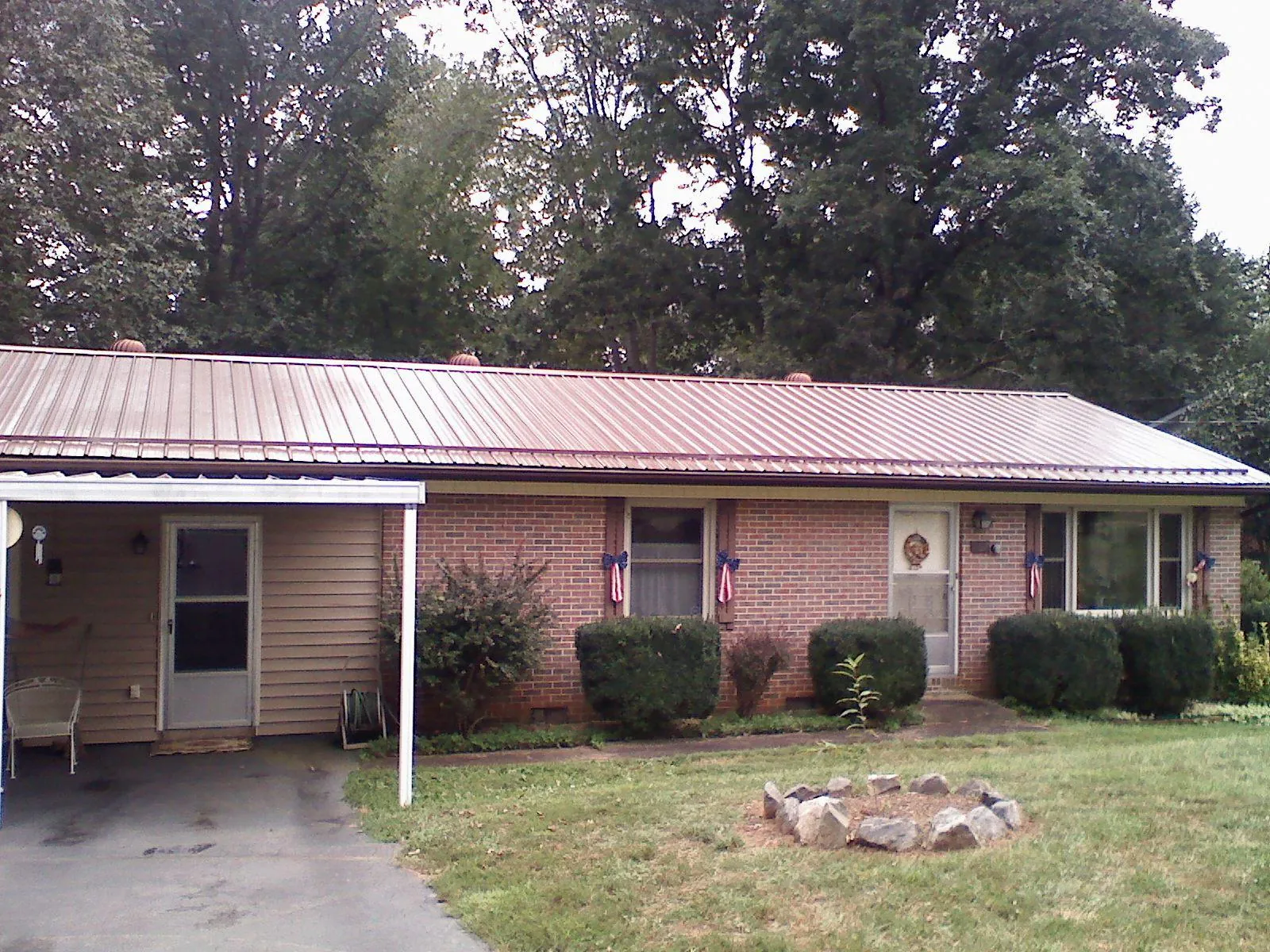 Bronze metal roof and carport on a brick ranch home — Roof Repair work by our crew in Pinckney